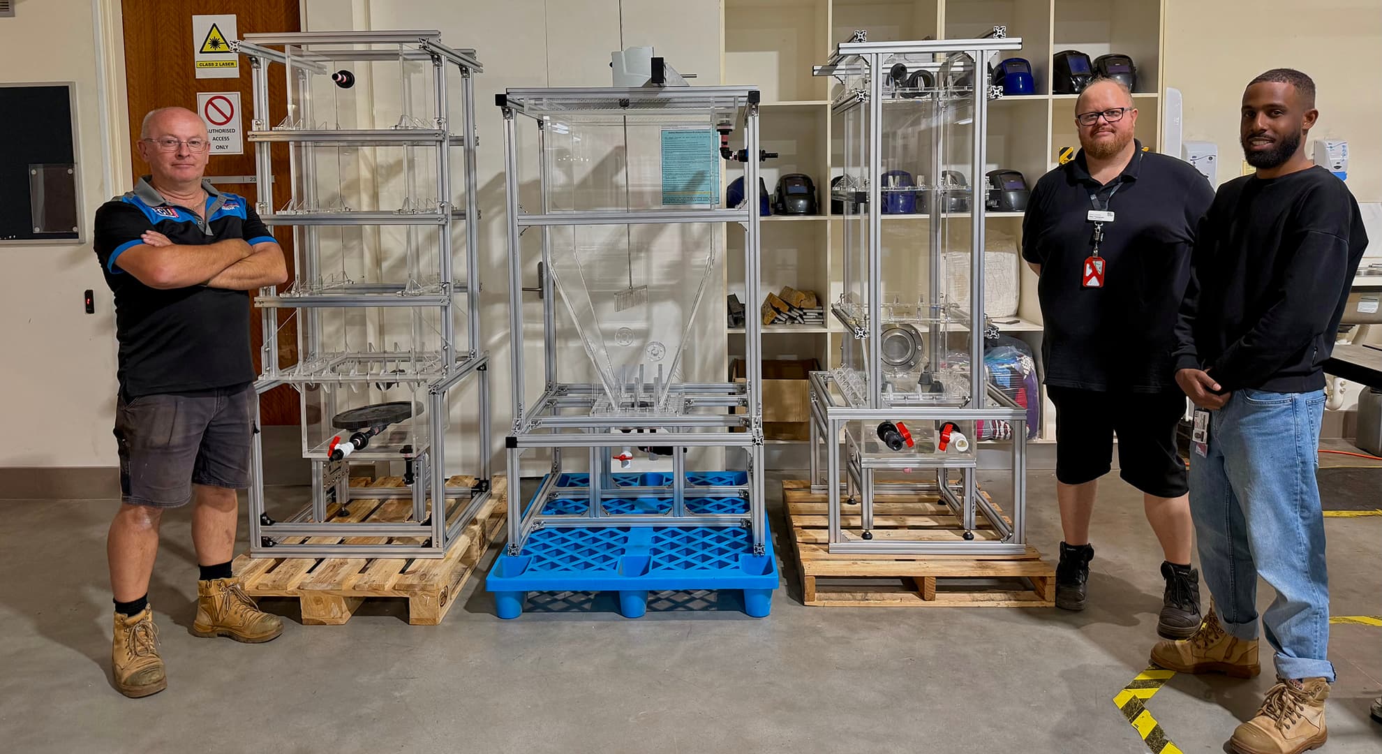 Three people standing by a water reactor