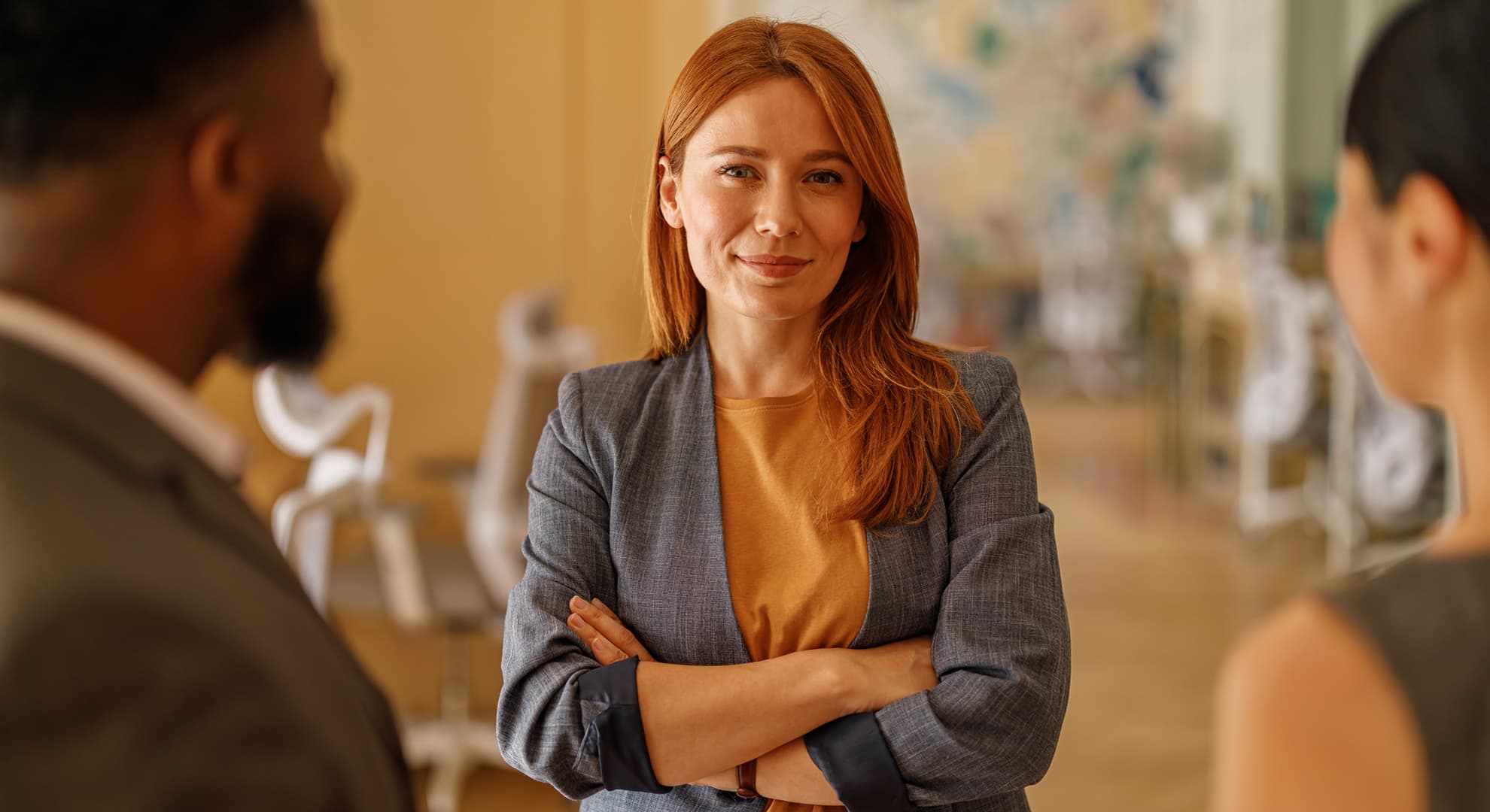 Female employee looking down camera with arms crossed.
