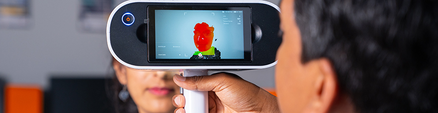 Man looking through handheld electronic device at woman behind screen