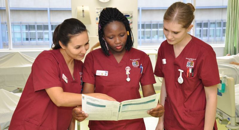 Three ECU nursing students looking at a medical chart.