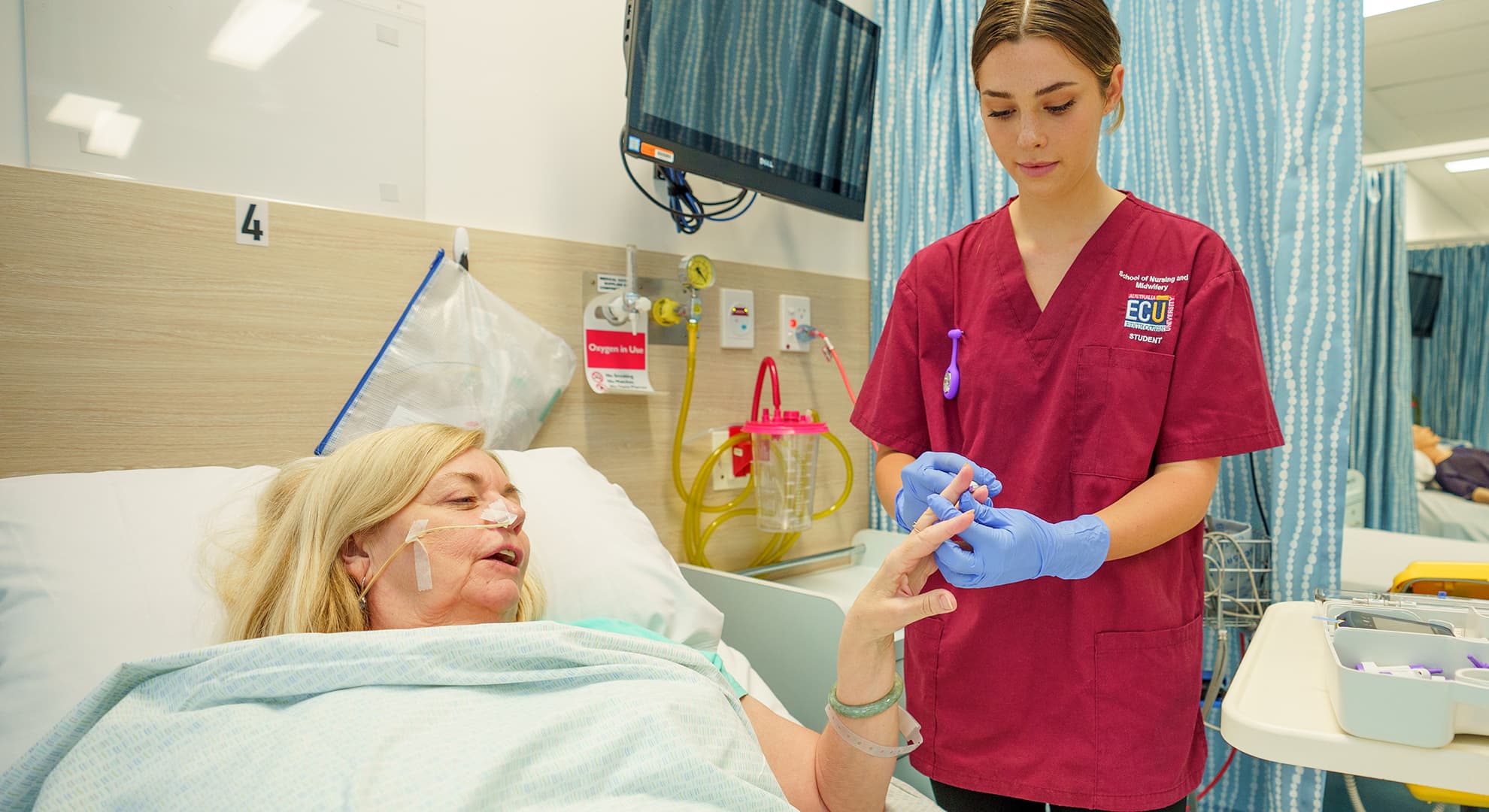 Student nurse standing next to a patient in bed.