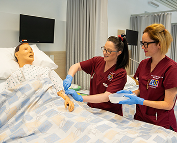 Two nursing students practice caring for a dummy patient lying in a bed in a student hospital setting. Search away with BMJ for great medical content! Find it in ECU Library's A-Z list of databases.