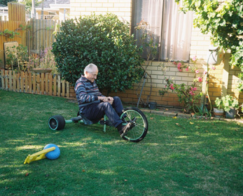 Man on tricycle in garden.