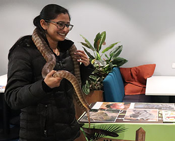 A smiling student has an experience with a native Australian reptile, which they are handling confidently.