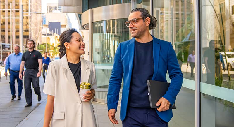 Two people walking down a street talking 