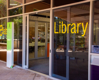 Entrance to the South West Library with glass sliding doors and large yellow “Library” signage visible from outside the building.