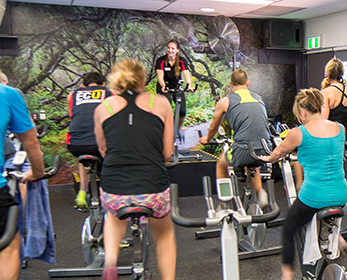 People participating in a group fitness cycling class