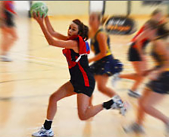 A woman catching a ball in a game of netball