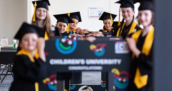 Children wearing graduation gowns and hats