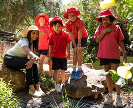 Teacher outside in garden with four primary school students