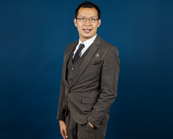 Dr Allen Au in front of a navy blue background