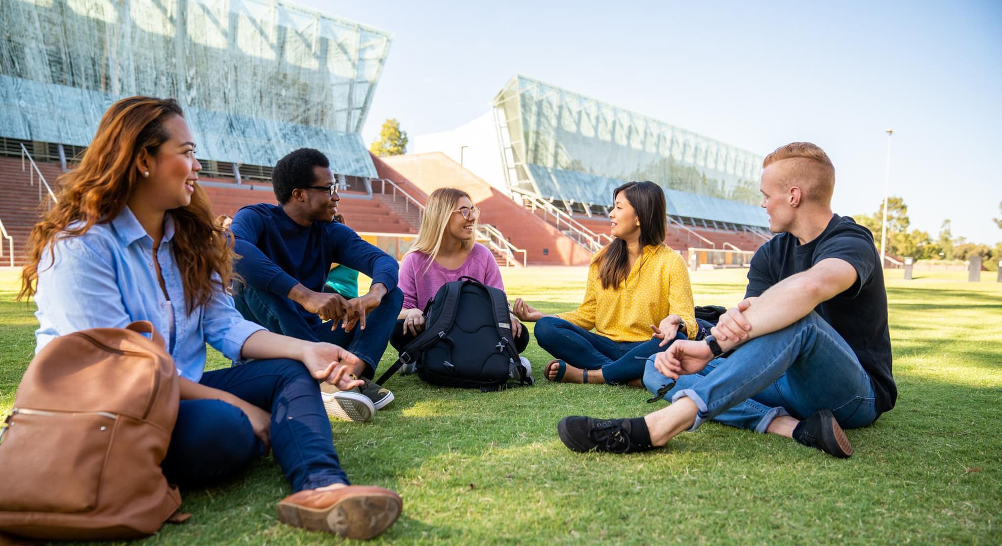 A group of ECU students sitting on the grass chatting to each other.