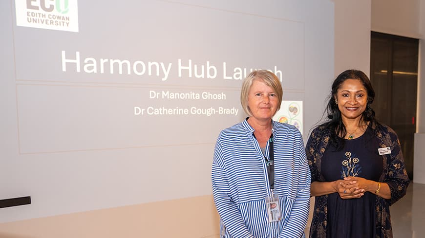 two women standing in front of a presentation screen.