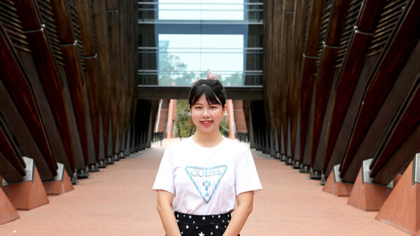 Female student standing in front of building 1.