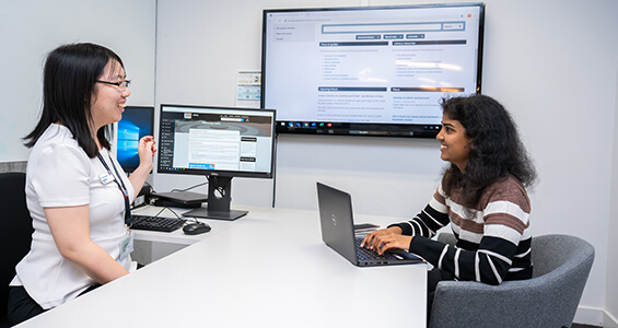 Library support staff showing student information on computer