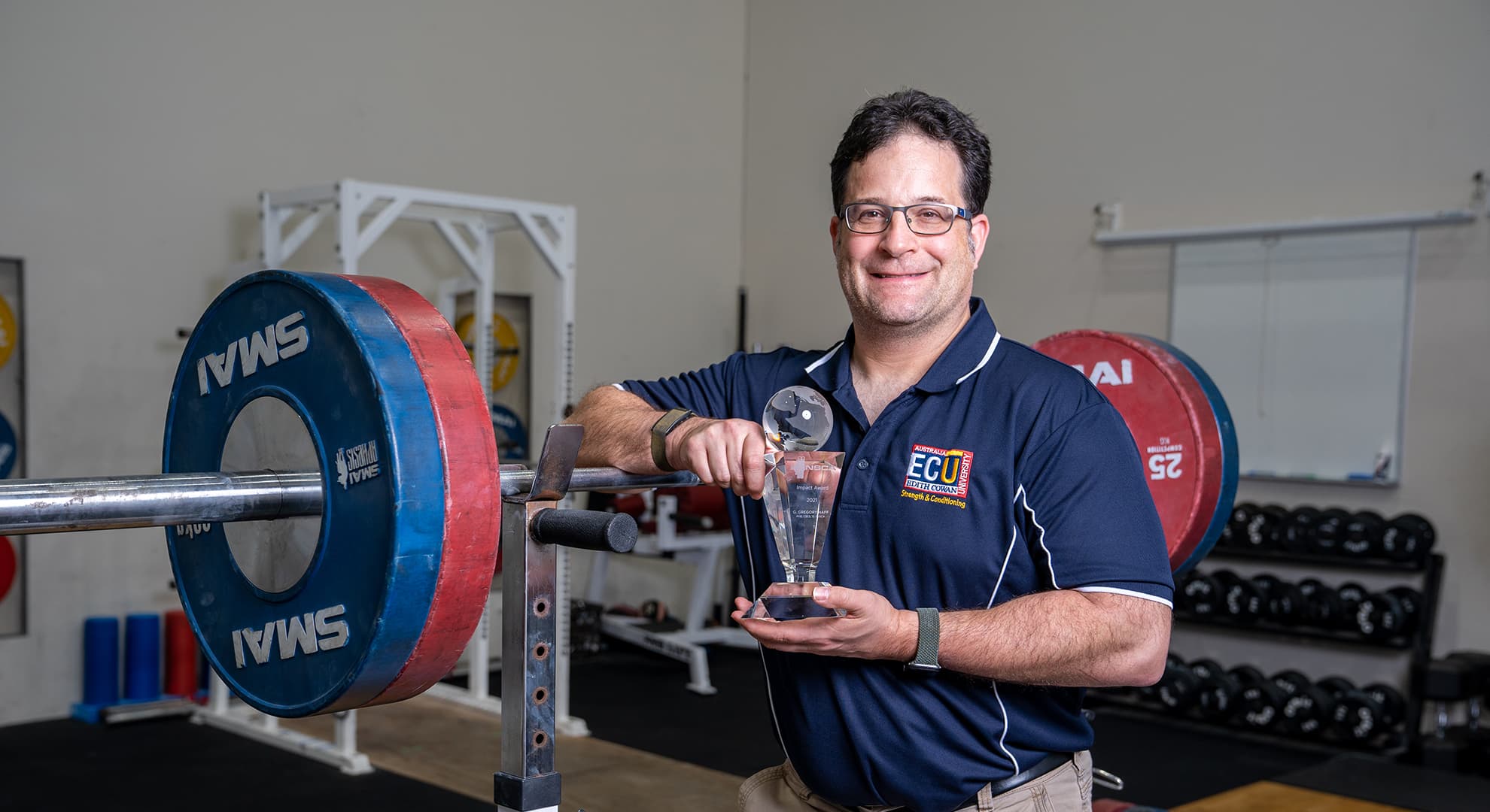 Man standing next to weight lifting equipment.