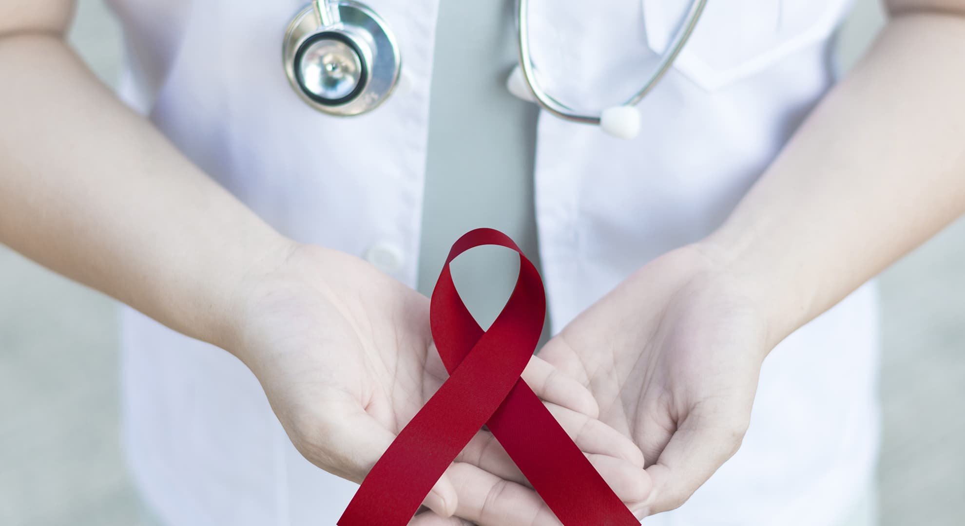 Healthcare worker holding a burgundy ribbon.