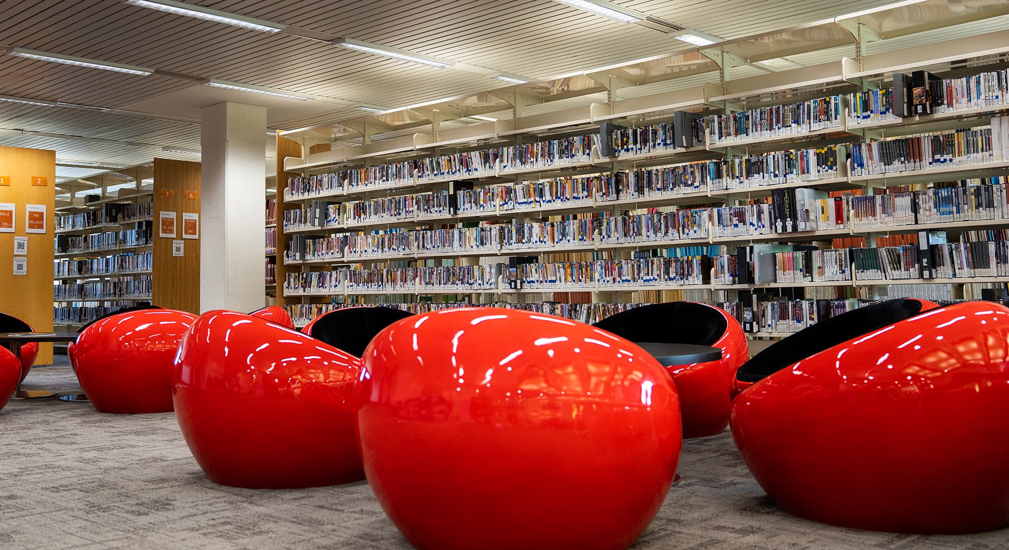 Racks of books behind bright red plastic chairs