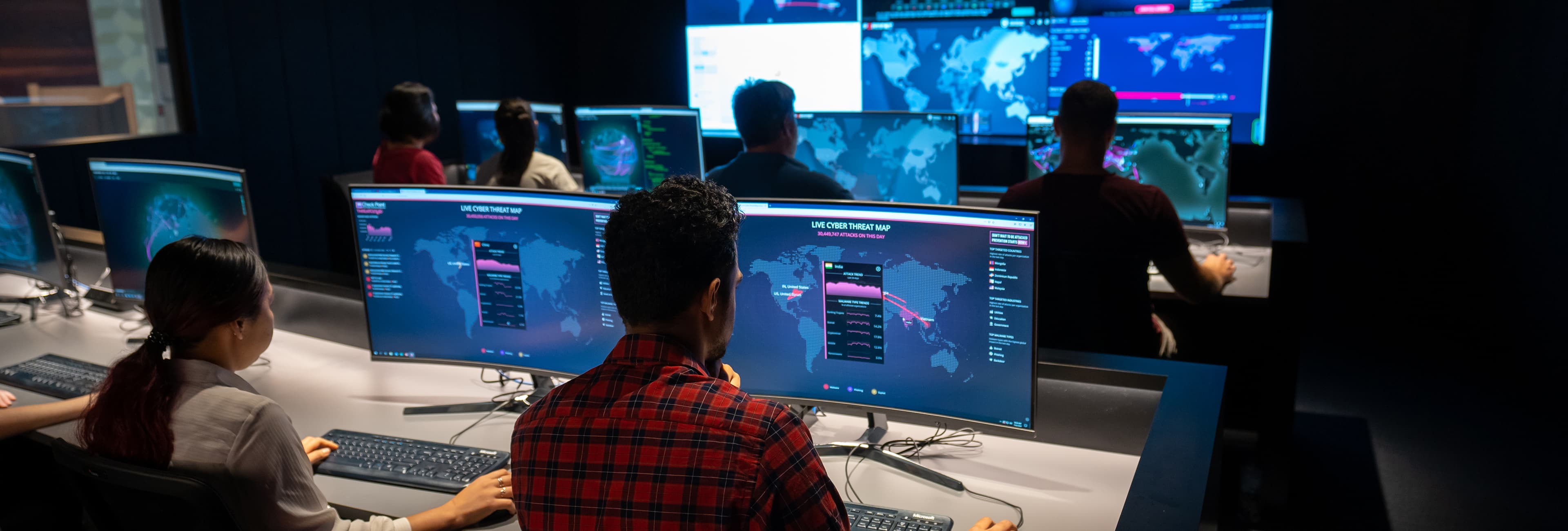 People sitting in front of computers in dark room