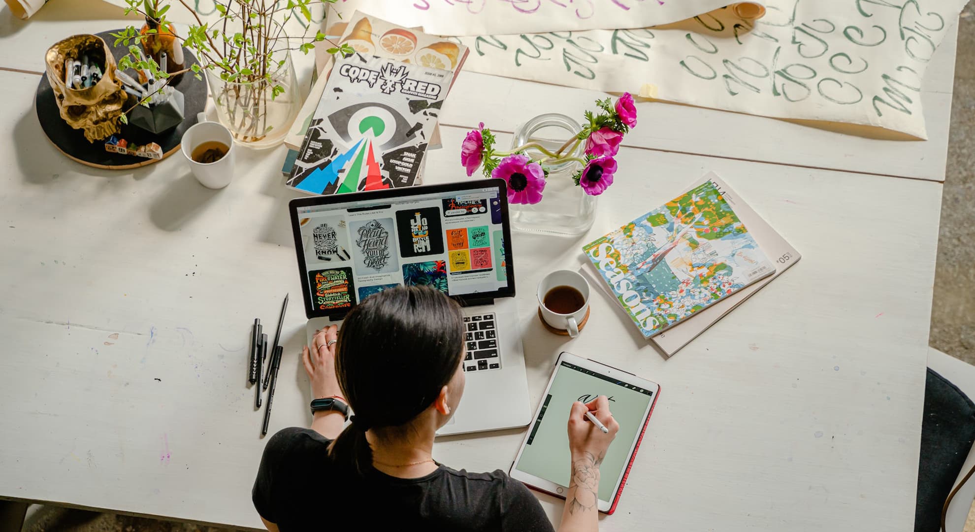 Woman sitting at a desk using a laptop and tablet.
