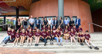 A large group of students wearing maroon t-shirts, smiling at the camera