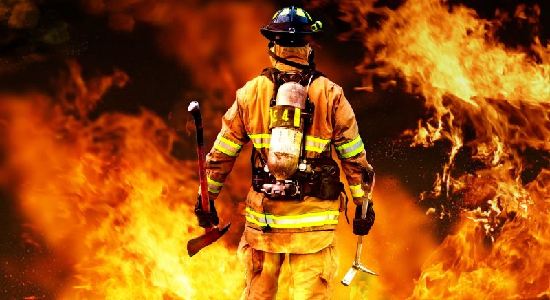 Firefighter standing in front of a wall of flames