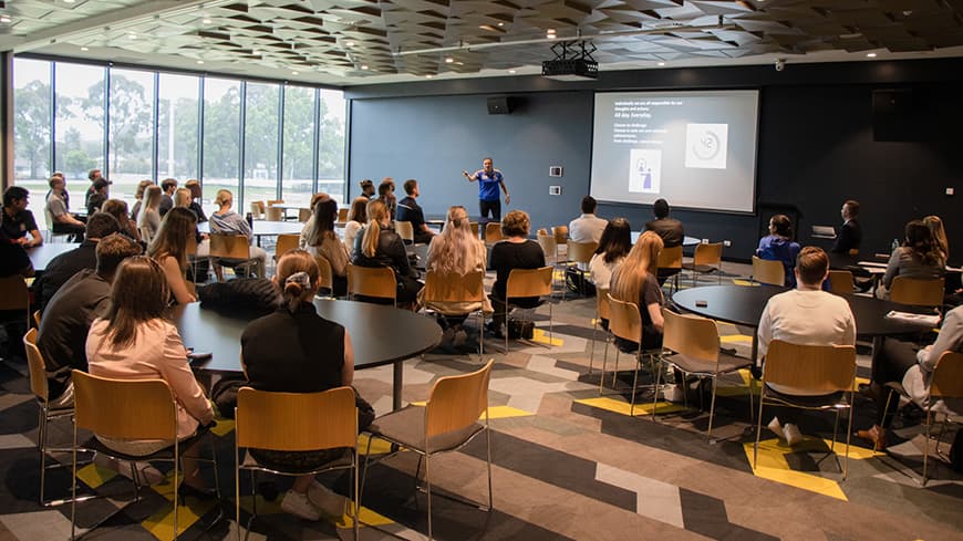 Man presenting to a group of students in a large room