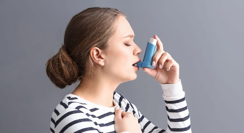 Woman using an asthma inhaler.