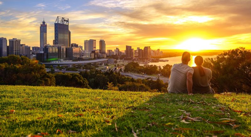 Man and woman watching sunrise over city of Perth