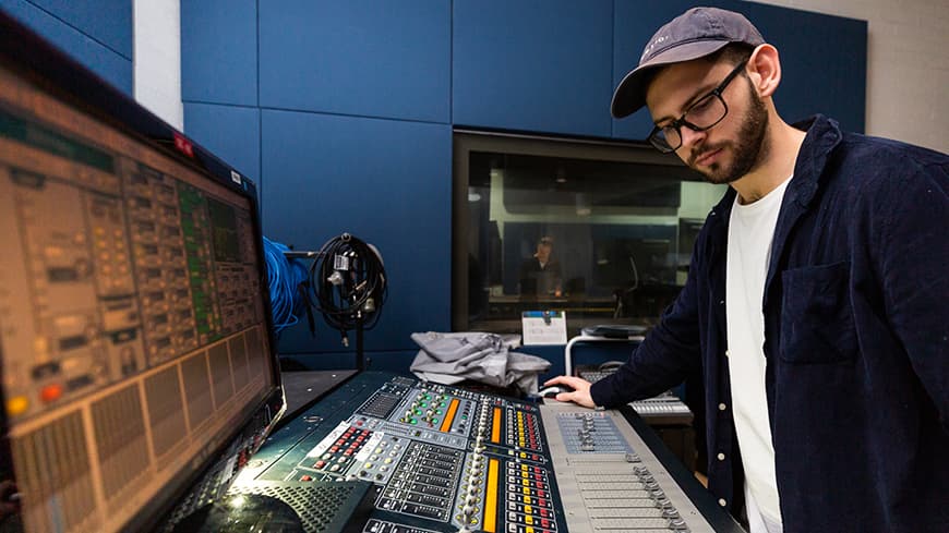 Male student standing at recording console