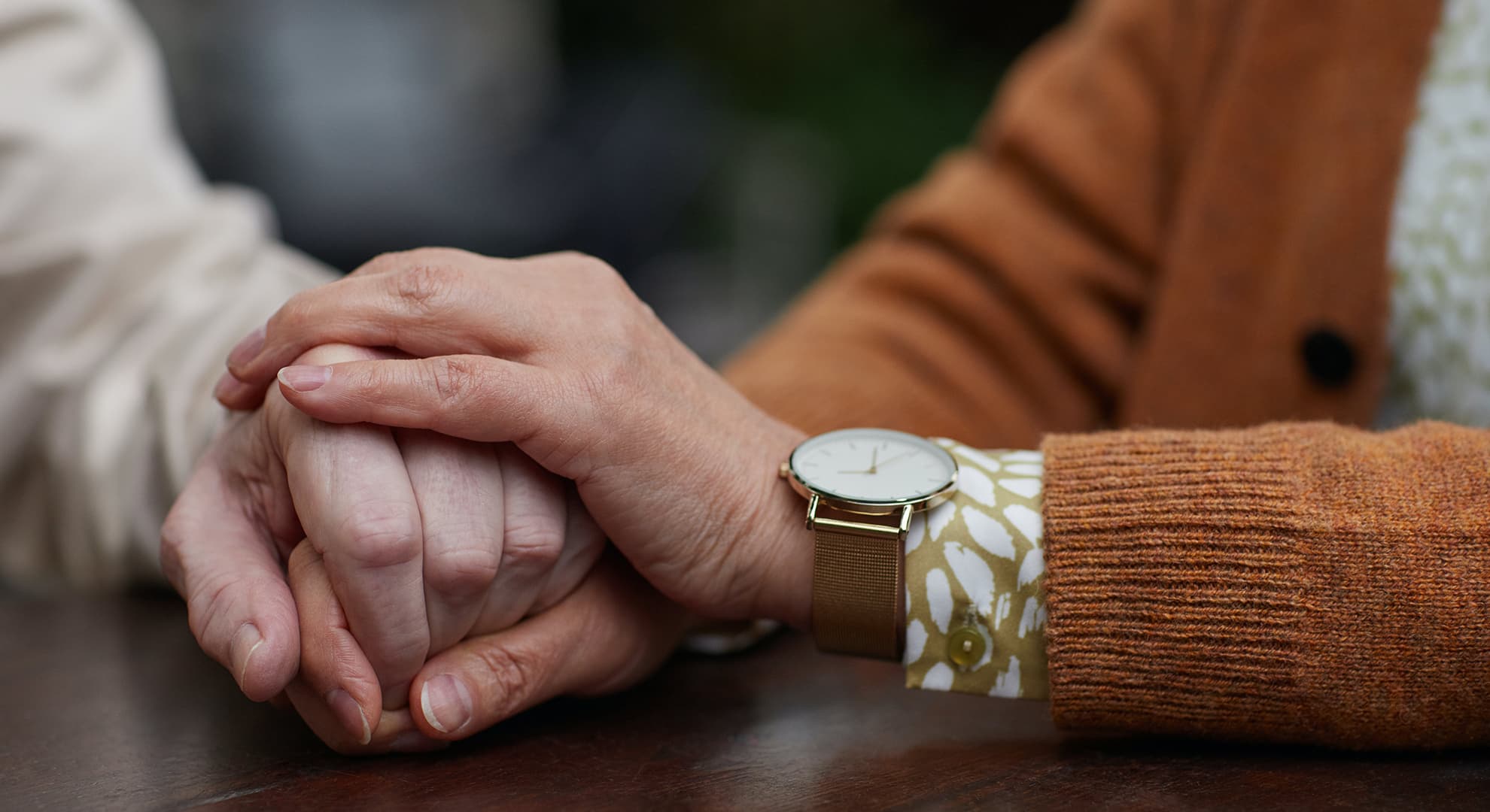 Person supportively holding an older person's hand.