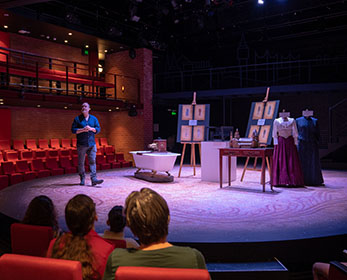 In a WAAPA theatre, students sit in the audience to learn about staging and props. A lecturer is presenting from the stage.