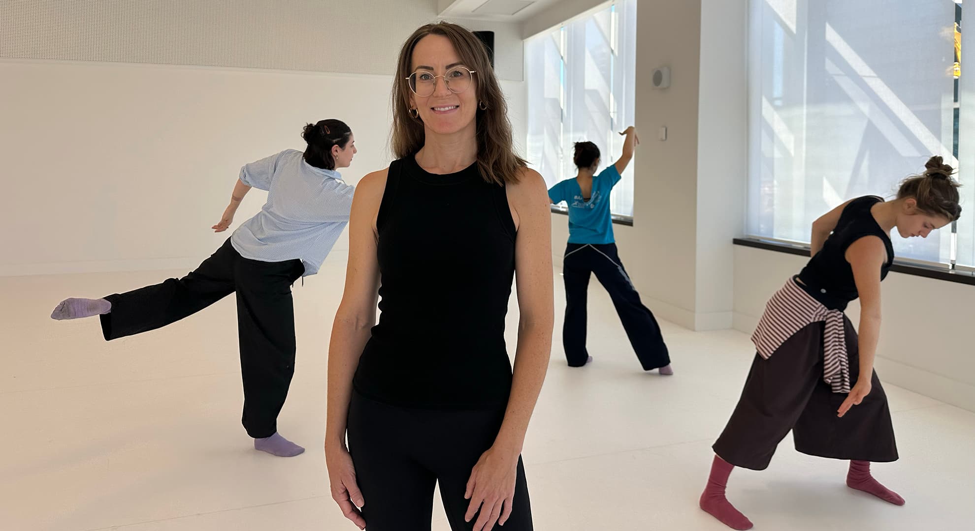 A dance studio with Dr Joanna Nicholas standing in the foreground with dancers behind.