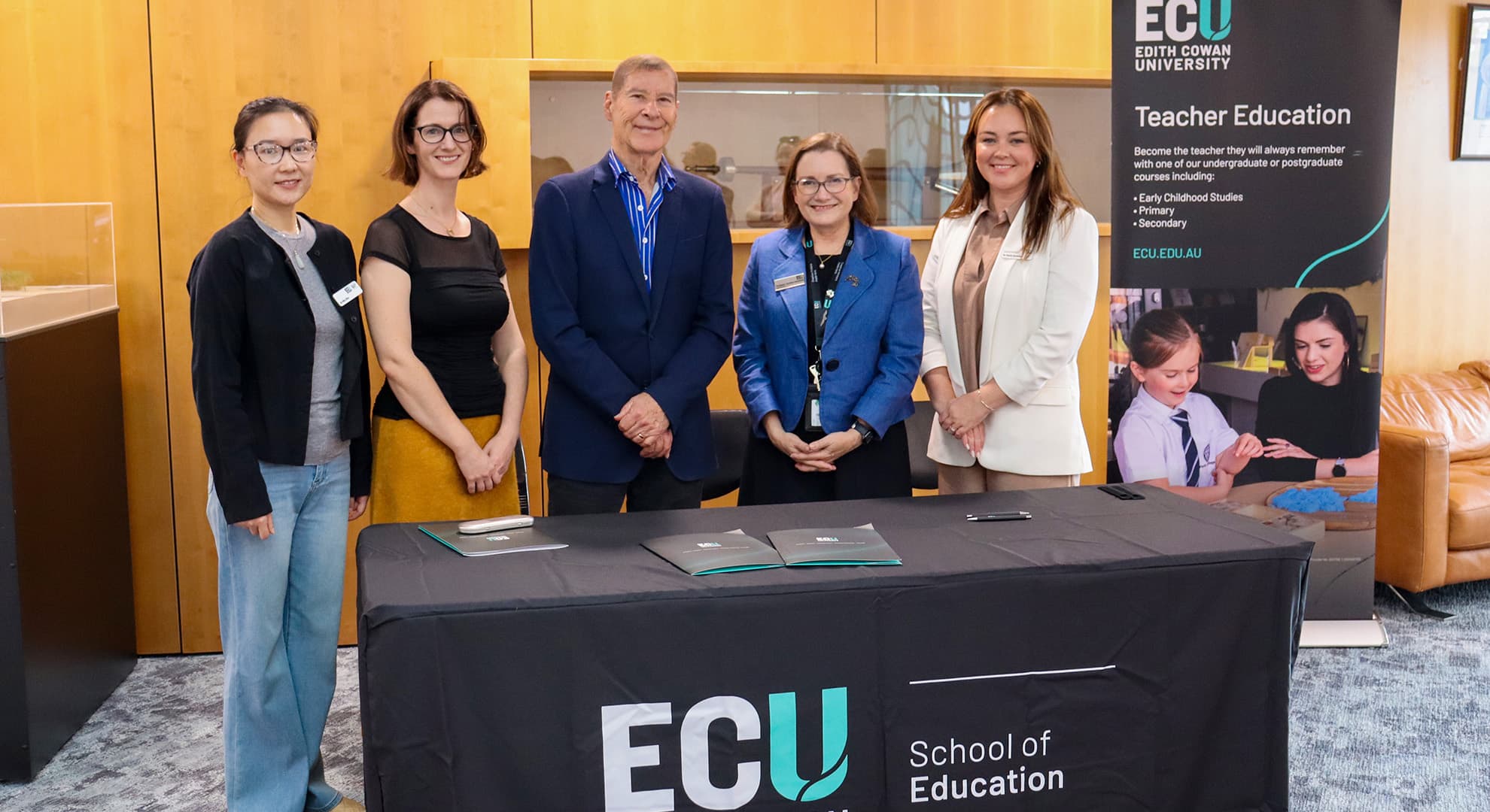 Five people standing behind a table with ECU branding.
