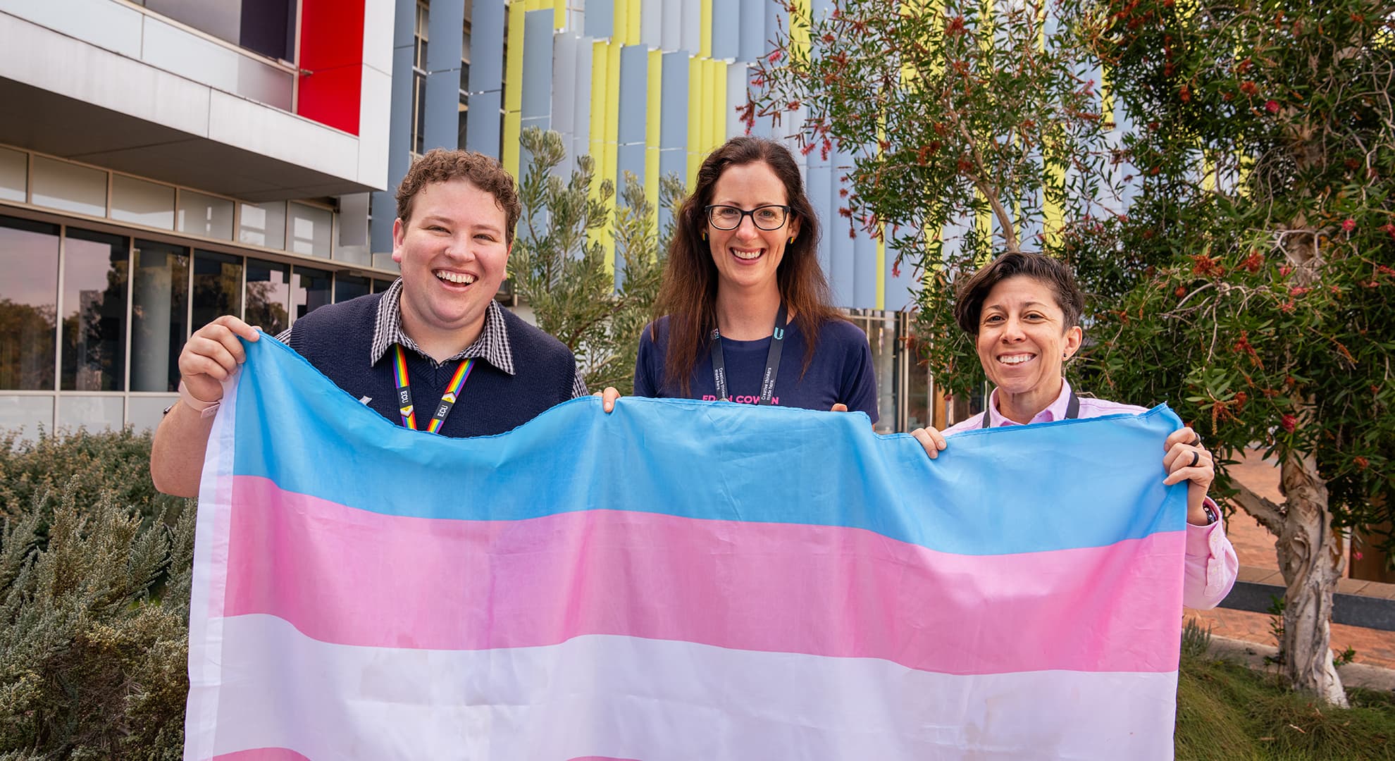 Three people holding a transgender flag