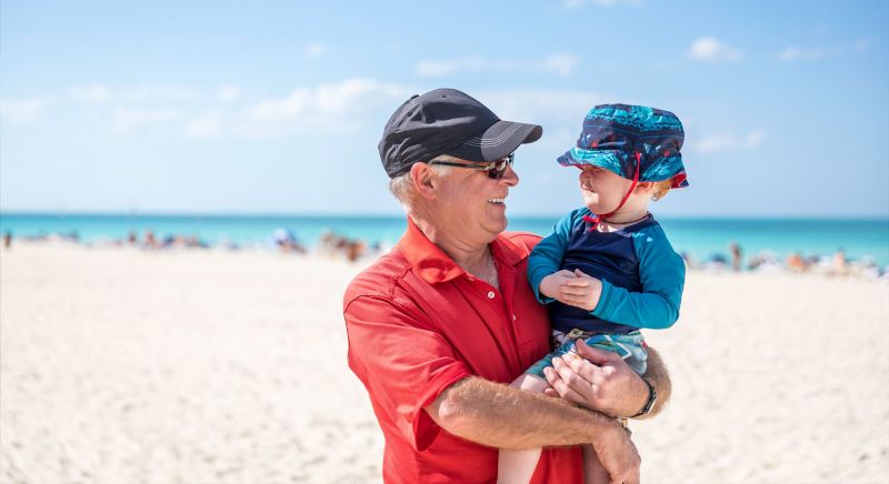 Grandfather holding baby boy on beach