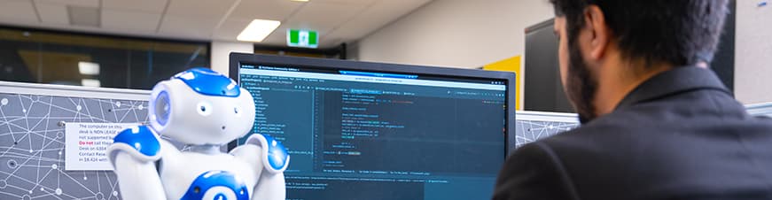 Man using a computer to program a robot.