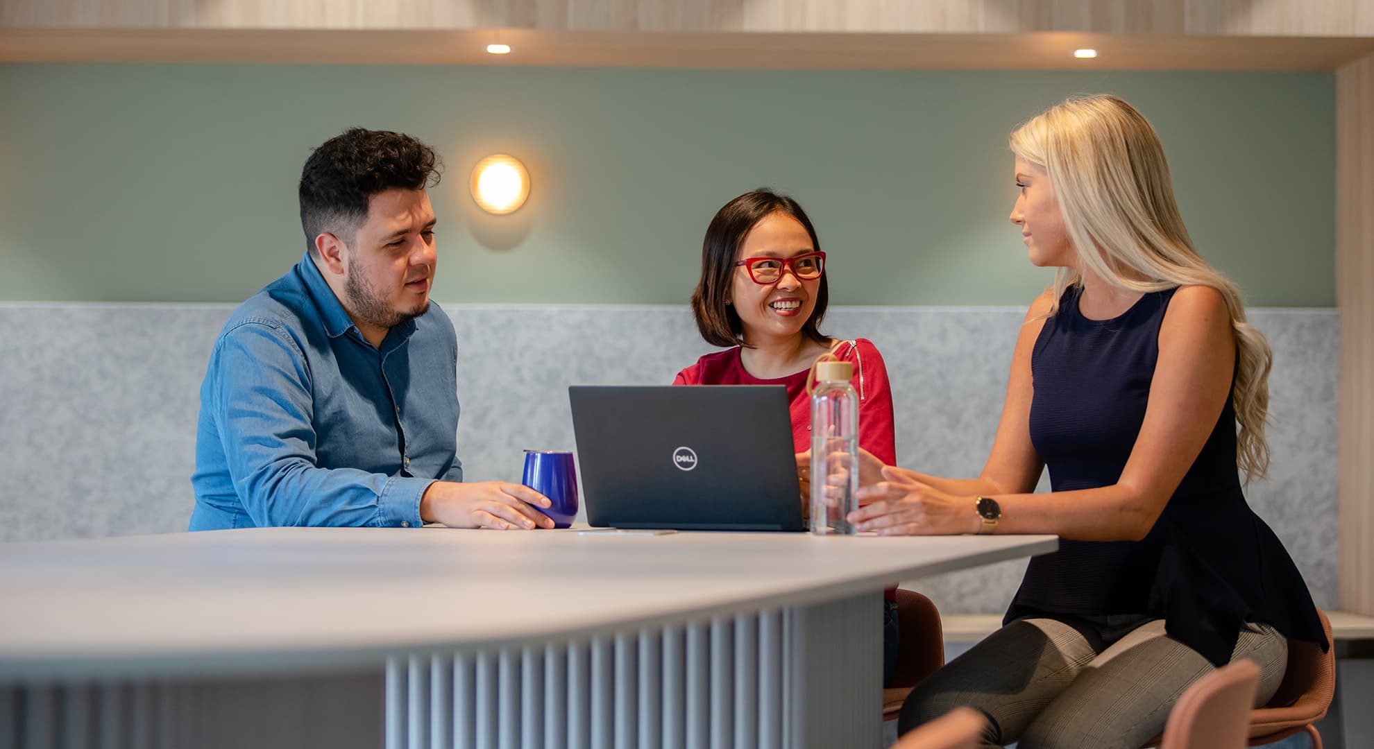 Three students sitting at a desk talking.