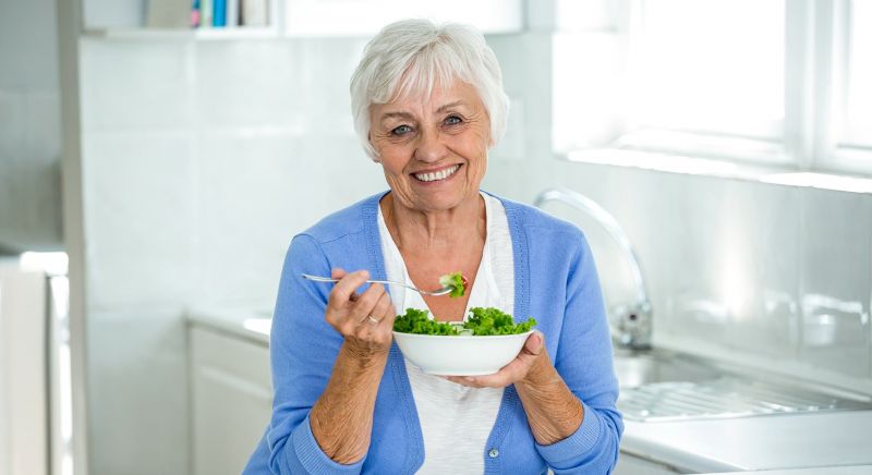 Older woman eating a green salad.
