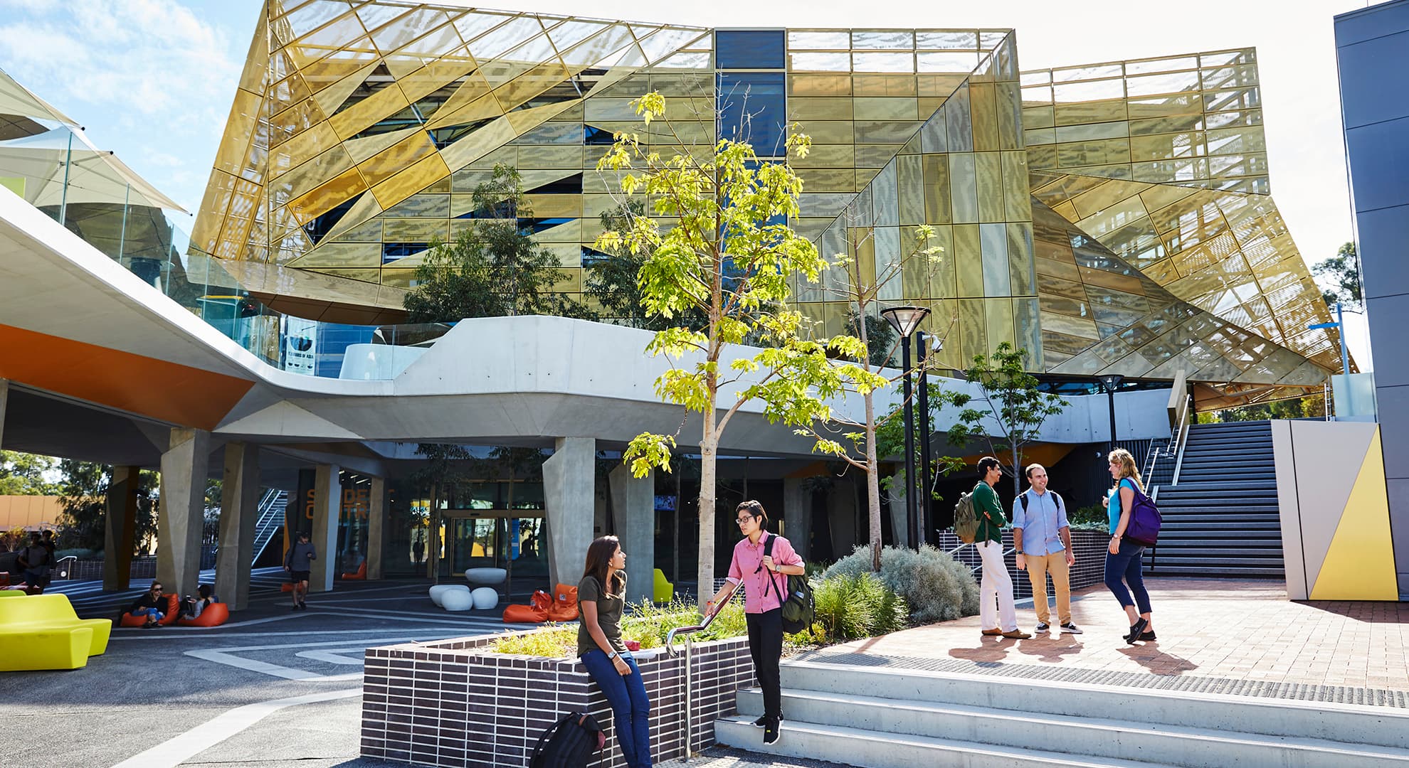 People standing on steps in front of a gold building.