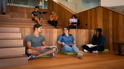 Students utilising the informal collaboration space on the new stairs in the new-look ECU Library.