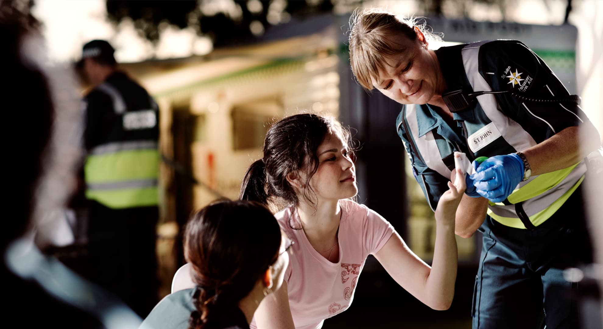 Female paramedic applying a bandage to hand of a young woman.
