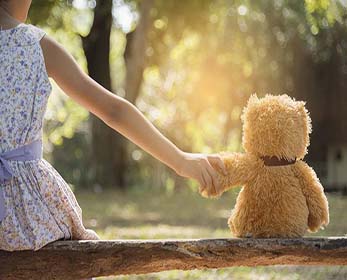 child holding the hand of a teddy bear
