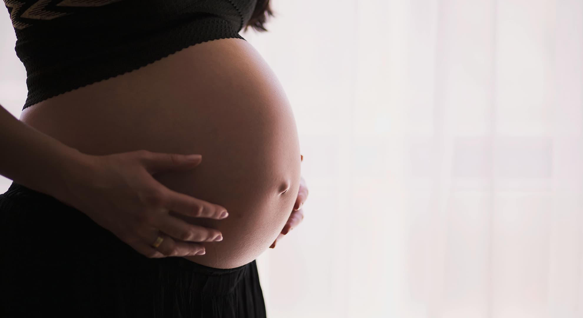 A woman holding her pregnant belly.