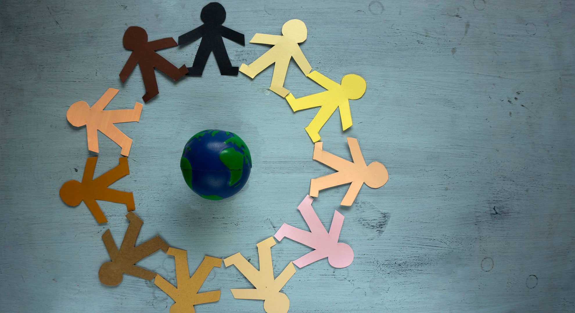 Paper people holding hands around a globe