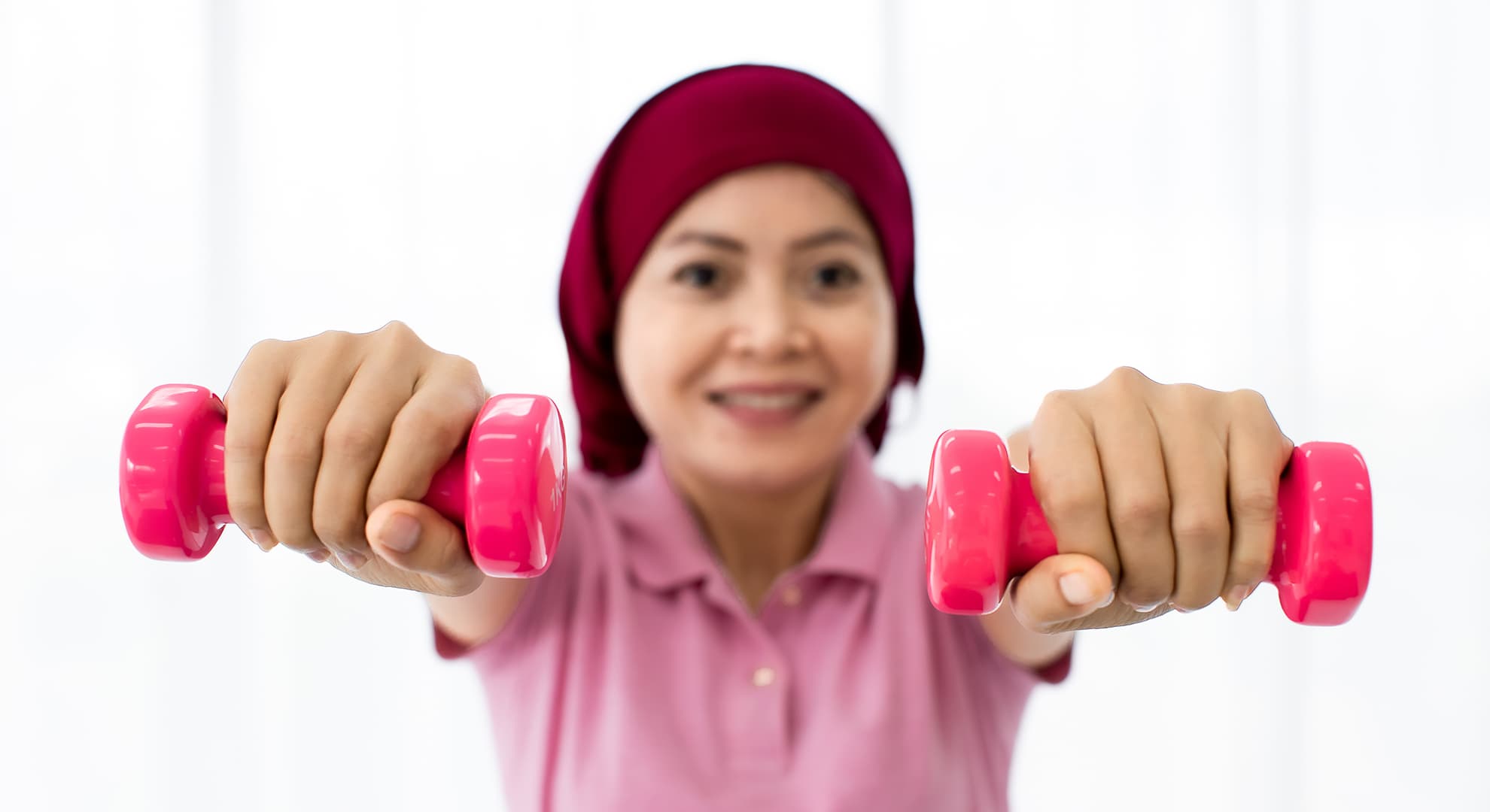 Female cancer patient holding up weights.