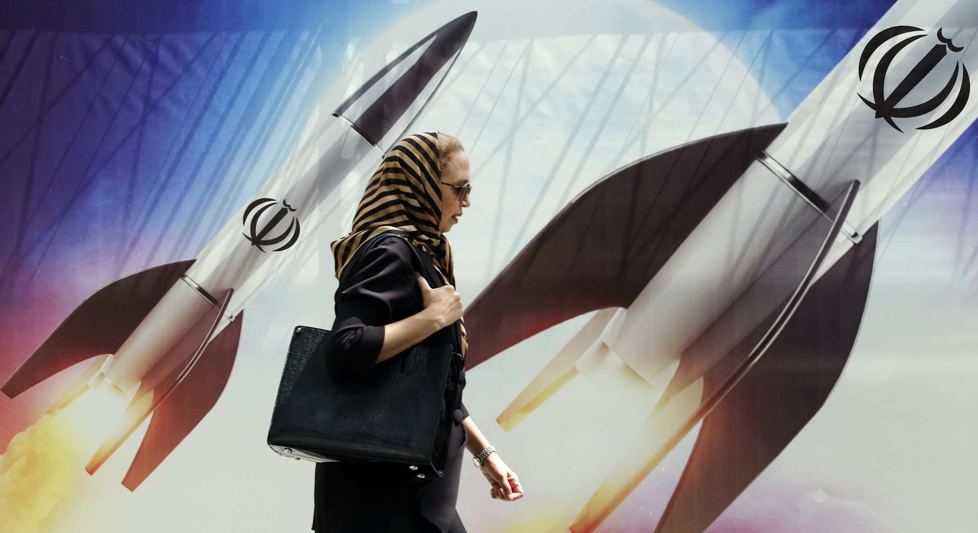 Woman walking with missiles in the background.