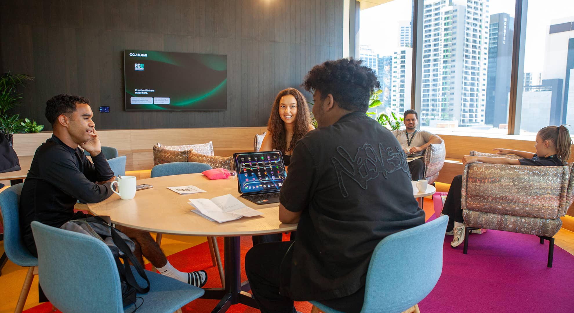 Group of Aboriginal Edith Cowan University students sitting together, smiling and collaborating in the Nala Kala room at ECU City Campus.