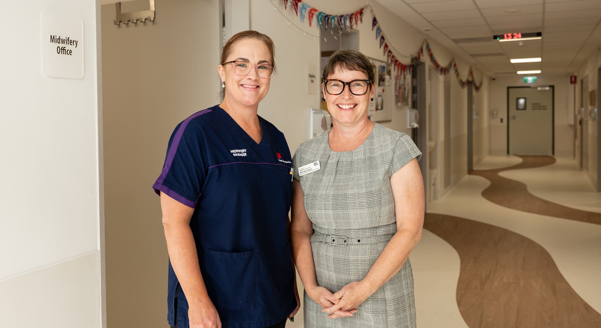 Two midwives standing in hospital corridor