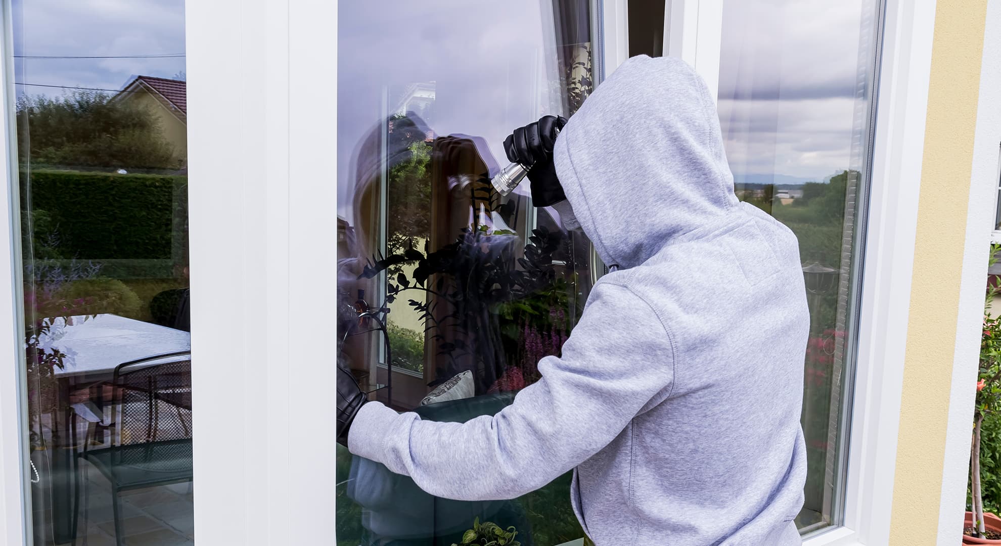 Burglar breaking into a home through a window.